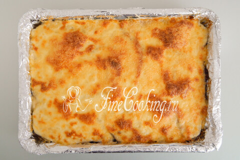 Форма с мусакой, посыпанной сыром, в разогретой духовке.
