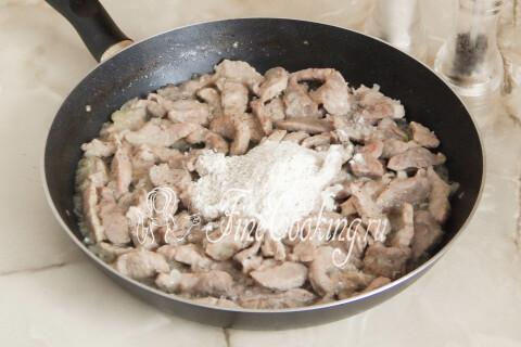 Мясо с луком, посыпанное пшеничной мукой на сковороде