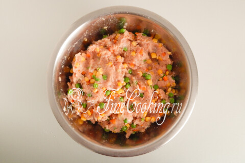 Мясной фарш с овощами и кукурузой, равномерно перемешанный в миске.