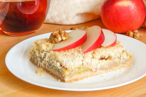 Насыпной яблочный пирог, нарезанный кусочками, на столе рядом с чаем