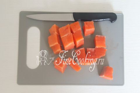 Кусочки филе форели, нарезанные небольшими кусками на разделочной доске.