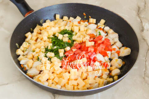 Мясная начинка в сковороде дополнена сыром, томатами и зеленью.