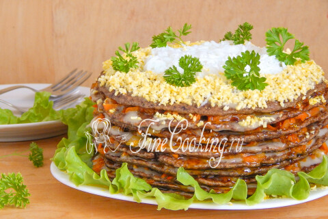 Разрезанный печёночный торт с яичной посыпкой и слоями начинки на тарелке