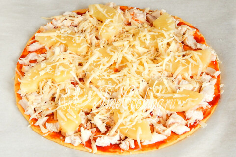 Пицца с курицей и ананасами посыпана тёртым сыром