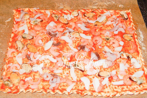 Морской коктейль, выложенный поверх томатного соуса