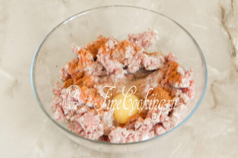 Мясной фарш в миске, смешанный с куриным яйцом, приправой, солью и перцем.