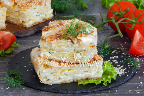 Пирог из лаваша с сыром и зеленью, нарезанный на порционные куски, на тарелке