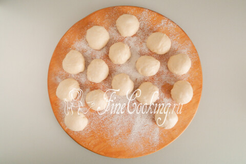 Дрожжевое тесто, разделённое на одинаковые шарики на присыпанной мукой доске.