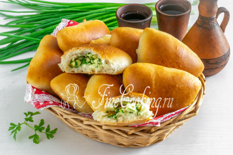 Румяные пирожки с яйцом и зеленым луком на тарелке, с тонкой корочкой.