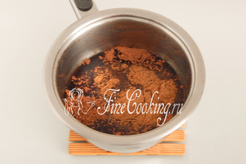 Какао-порошок и молотые пряности поверх карамельной жидкости в кастрюле.
