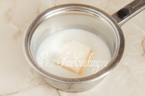 Молоко, вода и сливочное масло с солью и сахаром в кастрюле на плите.