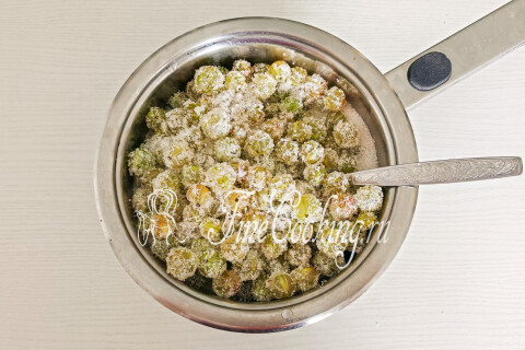 Крыжовник, засыпанный сахаром и водой, в кастрюле.