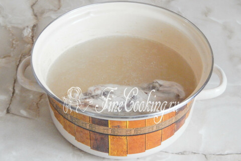 Кастрюля с бульоном, с поверхности которого шумовкой снимают пену