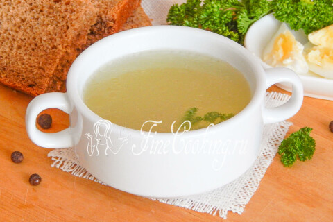Порция куриного бульона в тарелке, украшенная зеленью петрушки