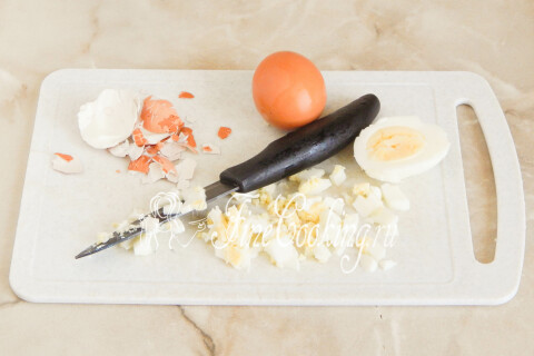 Отварные куриные яйца очищены и нарезаны мелким кубиком