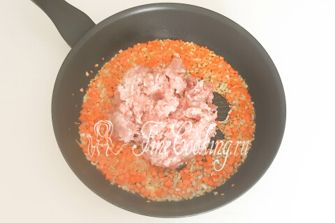 Мясной фарш с морковью и луком разбивается лопаткой на сковороде.