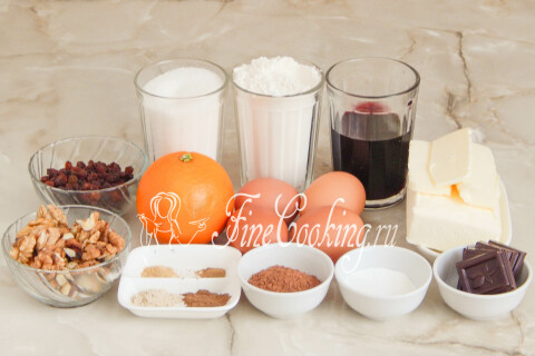Продукты для рождественского кекса: мука, сахар, яйца, красное вино, масло, апельсин, орехи, изюм, шоколад и какао