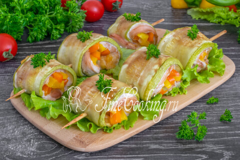 Готовые рулетики из кабачков с курицей, сыром и овощами на тарелке