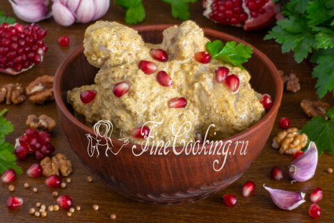 Сациви из курицы под ореховым соусом подано с зёрнами граната и кинзой.