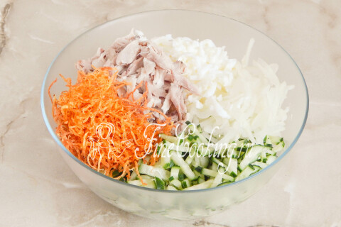 Огурцы, лук, курица, яичные белки и картофельная соломка сложены в миске.