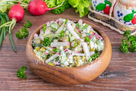 Салат с редиской, горошком и яйцом в тарелке на столе