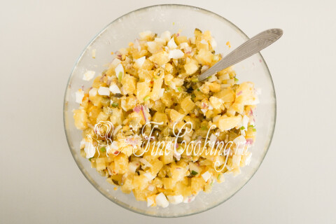 Перемешанный картофельный салат с огурцами и яйцами в миске.