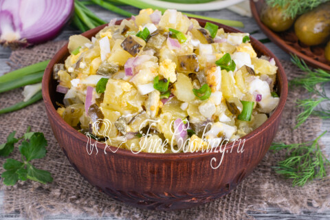 Картофельный салат с солёными огурцами и яйцами, поданный в миске.