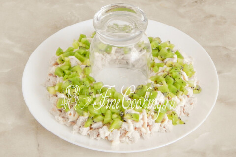 Кусочки киви, выложенные вторым слоем поверх кубиков курицы в блюде.