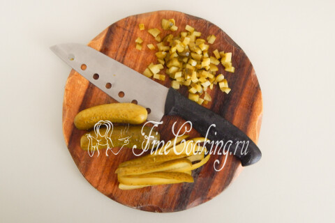 Маринованные огурцы, нарезанные мелким кубиком на доске