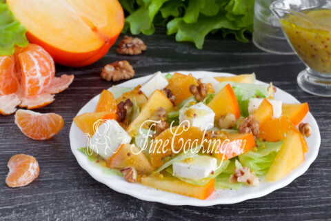 Готовый салат с хурмой, мандаринами и брынзой на тарелке