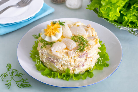 Салат с кальмарами, яйцом и сыром на тарелке, разложенный порционно