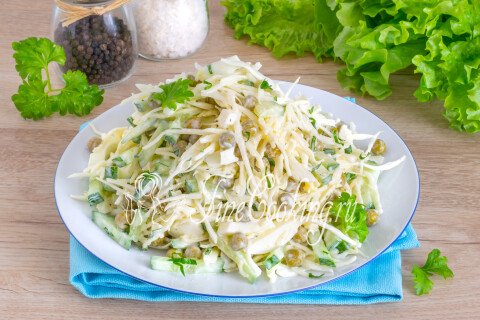 Овощной салат с капустой, горошком, огурцом и яйцами на тарелке.