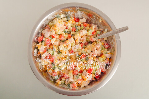 Готовый салат с копчёной курицей перемешивается ложкой перед подачей.