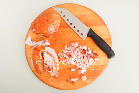 Куриные яйца в кастрюле с холодной водой, рядом нарезанная кубиком копчёная курица.