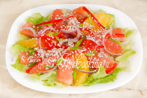 Салат с красной рыбой и цитрусовыми, политый заправкой и посыпанный кунжутом