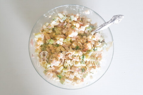Салат с морепродуктами и яйцами, перемешанный в миске.
