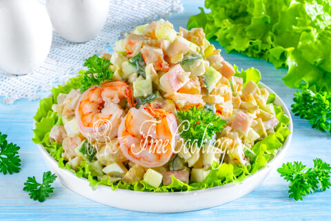 Готовый салат с креветками, кальмарами, огурцом и яйцами в салатнице.