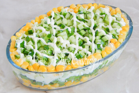 Салат с кукурузой и щавелем украшен сверху сеточкой из майонеза и кукурузой
