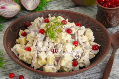 Салат с курицей и яблоками, украшенный клюквой и веточкой укропа