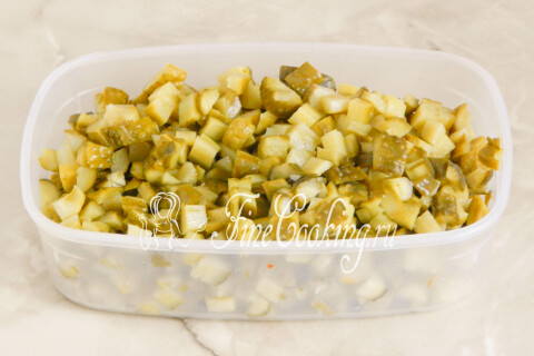 Маринованные огурцы, нарезанные мелким кубиком на разделочной доске