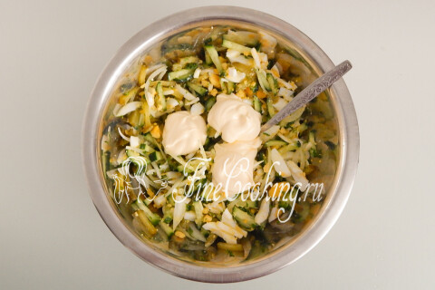 Майонез, выложенный ложкой поверх овощей с яйцами в миске.