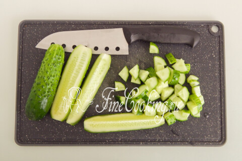 Свежие огурцы, нарезаемые произвольными кусочками на доске