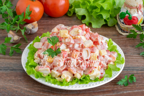 Готовый салат с помидорами, крабовыми палочками, яйцами и сыром на тарелке