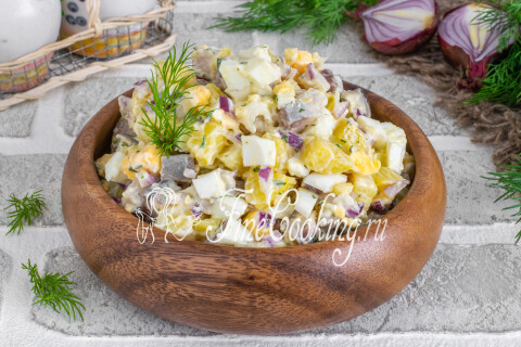 Салат с селёдкой, картофелем и яйцами в салатнице на праздничном столе