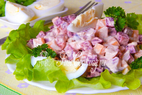 Готовый салат со свеклой, сыром и селедкой, украшенный свежей петрушкой