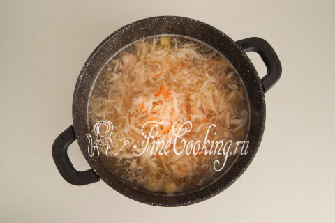 Квашеная капуста, добавленная в кастрюлю с бульоном и мясом