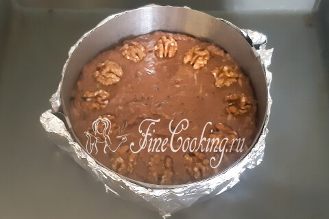 Тесто в форме, разровненное и украшенное половинками грецкого ореха.