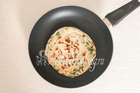 Заготовка лепёшки с луком румянится на сковороде при частом переворачивании.
