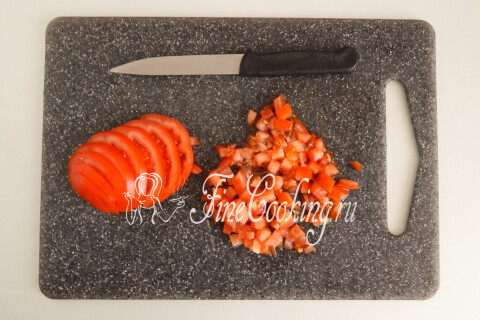 Помидор, нарезанный мелким кубиком, на разделочной доске.