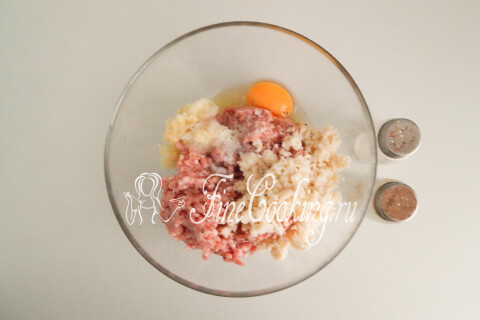 Мясной фарш в миске с размоченным батоном, яйцом, луково-чесночной кашицей, солью и перцем